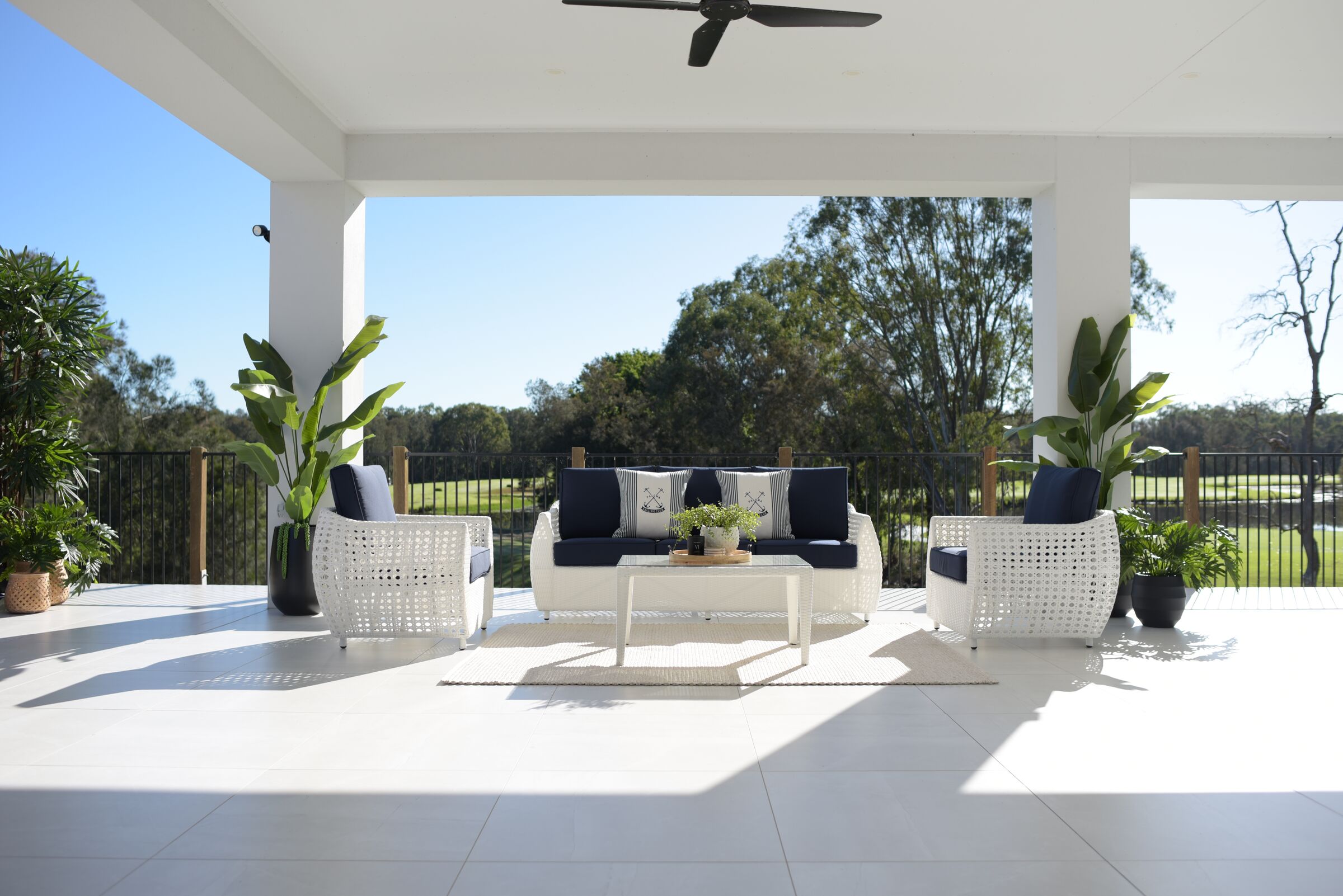 White wicker Voyage outdoor lounge setting with navy cushions under a covered alfresco
